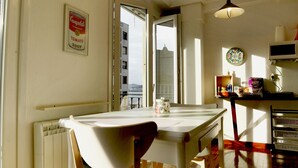 Une cuisine avec une table à manger, des chaises, un radiateur, une fenêtre donnant sur un beau paysage et un luminaire suspendu.