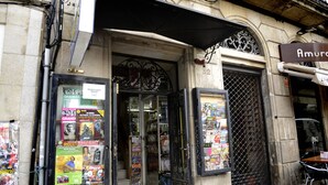 Une devanture de magasin avec une porte vitrée, des affiches et un portail en métal.