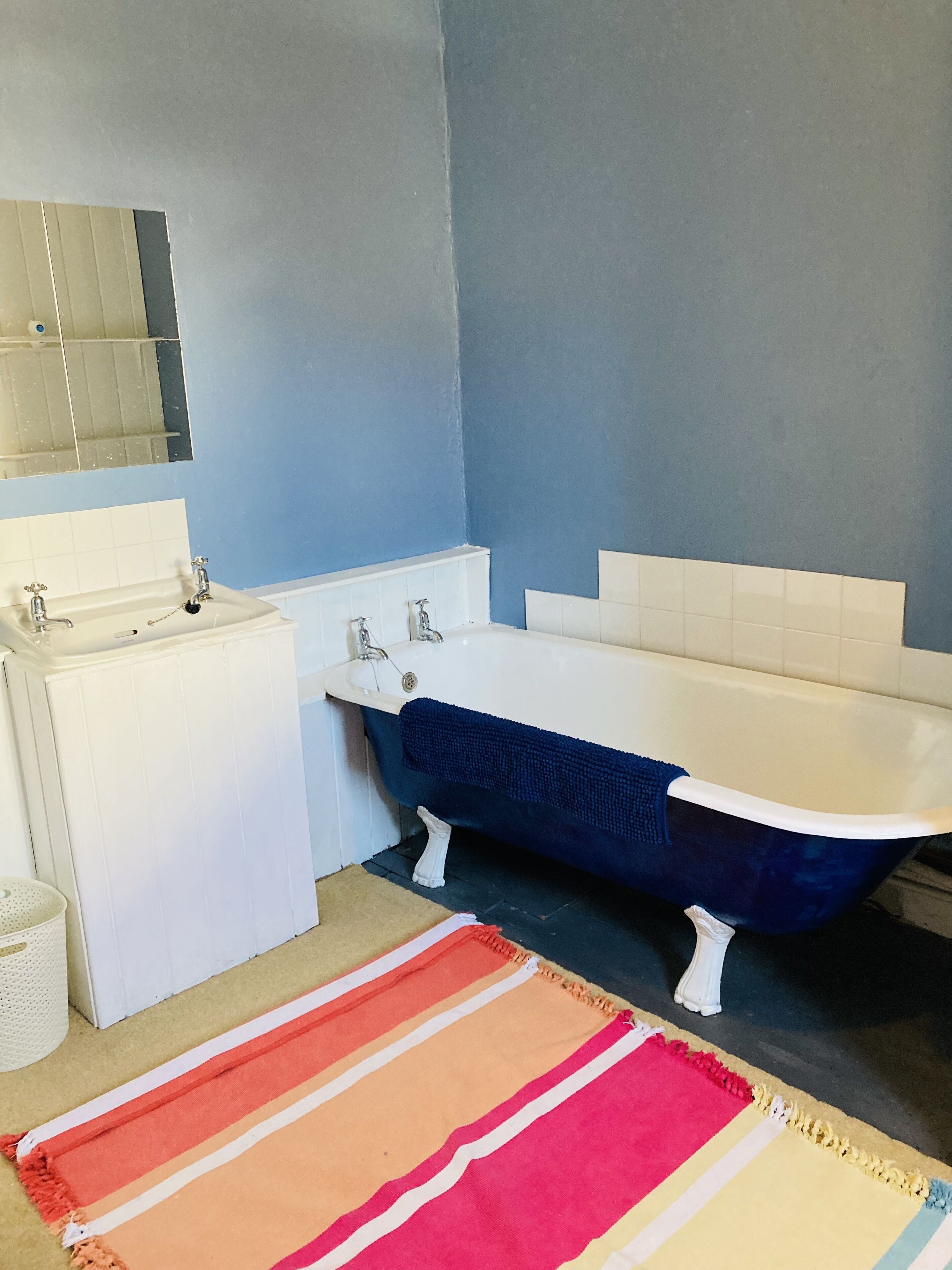 A bathroom with a white sink, a white bathtub, and a blue shower curtain.
