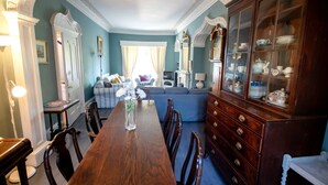 A dining room with a wooden table and chairs, a blue sofa, and a china cabinet. - Beautiful Historic Grade II Listed Georgian Town House (Llandeilo)