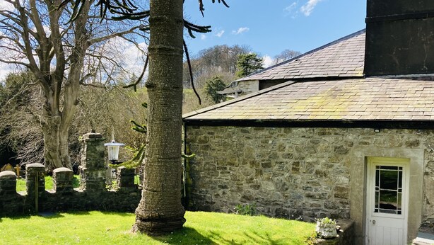 A stone building with a door and a small window, surrounded by a grassy area and trees. - Beautiful Historic Grade II Listed Georgian Town House (Llandeilo)