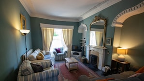 A living room with a fireplace, striped sofas, a coffee table, and a large mirror. - Beautiful Historic Grade II Listed Georgian Town House (Llandeilo)