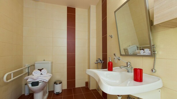 A bathroom with a toilet, bidet, sink, and mirror.