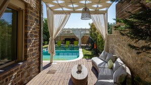 A covered outdoor area with a pool, seating, and a pergola.