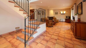 A spacious living area with a staircase, leather armchairs, and a fireplace. - Beautiful private villa for 8 people with private pool, TV, patio, pets allowed and panoramic view (L'ampolla)