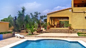 A swimming pool with a clear blue water, surrounded by a patio area with chairs and a small table. - Beautiful private villa for 8 people with private pool, TV, patio, pets allowed and panoramic view (L'ampolla)