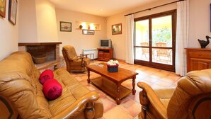 A living room with a leather sofa, a wooden coffee table, a fireplace, and a television. - Beautiful private villa for 8 people with private pool, TV, patio, pets allowed and panoramic view (L'ampolla)