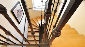 Una escalera de madera con barandales de metal negro y un cuadro en la pared.