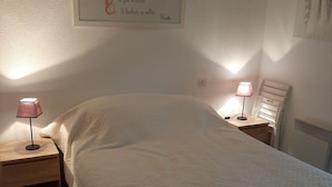 Quarto com uma cama, duas mesas de cabeceira e uma luminária na parede.