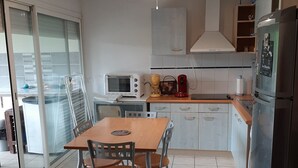 Uma cozinha com mesa de jantar, cadeiras, micro-ondas, cafeteira e geladeira.
