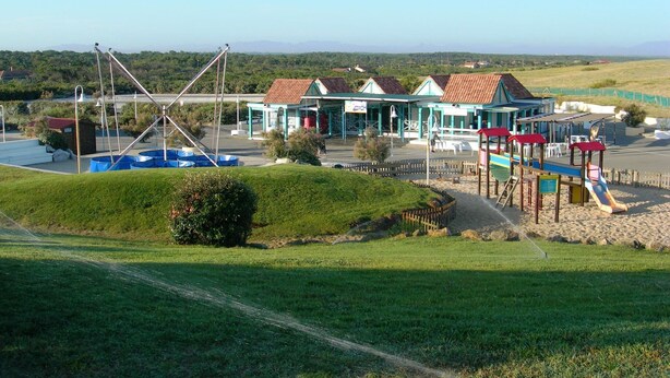 Um edifício à beira-mar com vários quartos, piscina e parque infantil.