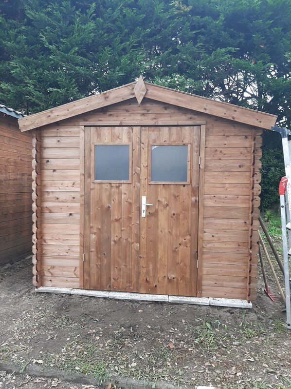 A wooden shed with a gabled roof and two square windows.