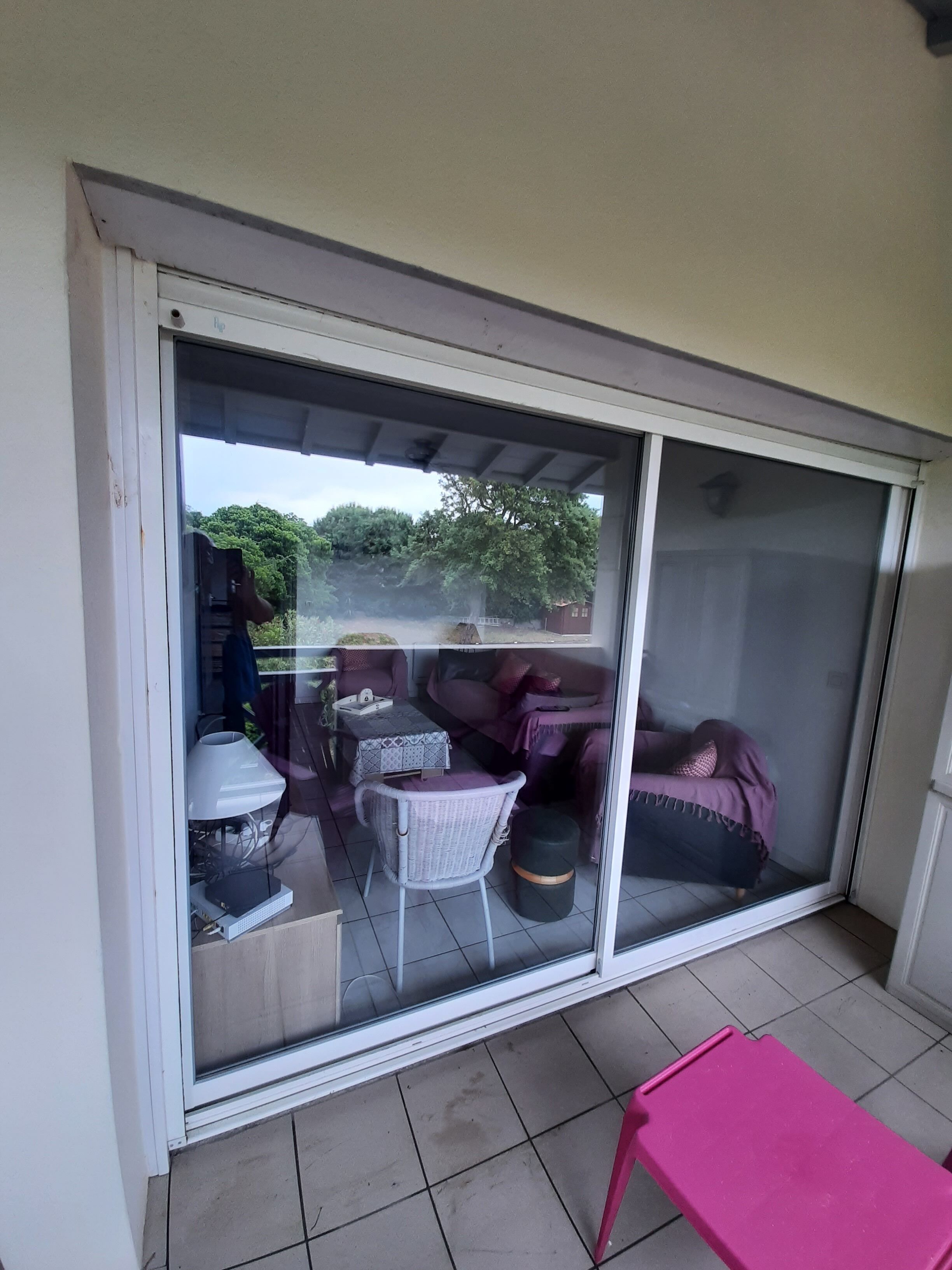 Et værelse med en skydedør, der fører til et udendørs opholdsområde med et bord, stole og en sofa.