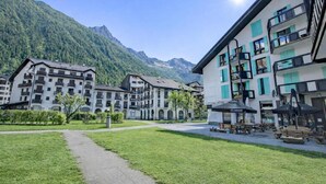 Een hotelhof met een verhard pad, buitenmeubels en uitzicht op bergen.