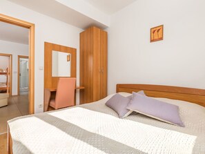 Un dormitorio con una cama, un armario de madera, un escritorio y una silla.