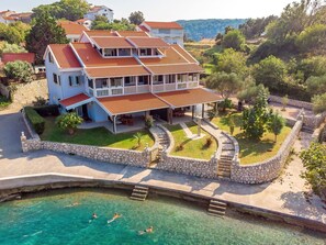 Una casa de varios pisos con piscina, muros de piedra y jardín.