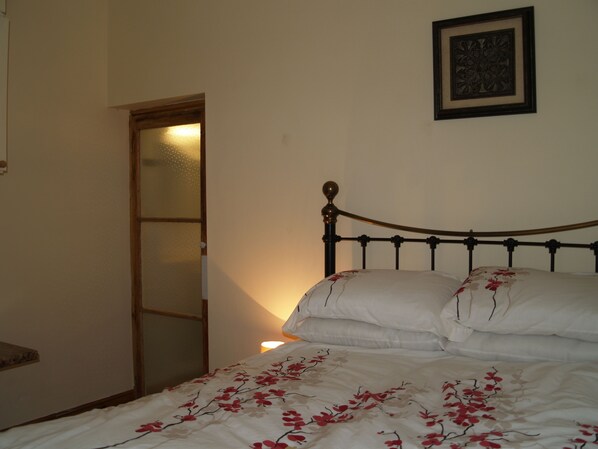 A bedroom with a bed, a door, and a wall-mounted picture. - Spacious Period Home With Private Walled Courtyard (Ventnor)
