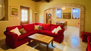 Una sala de estar acogedora con un sofá rojo, una mesa de centro de madera y un ventilador de techo.