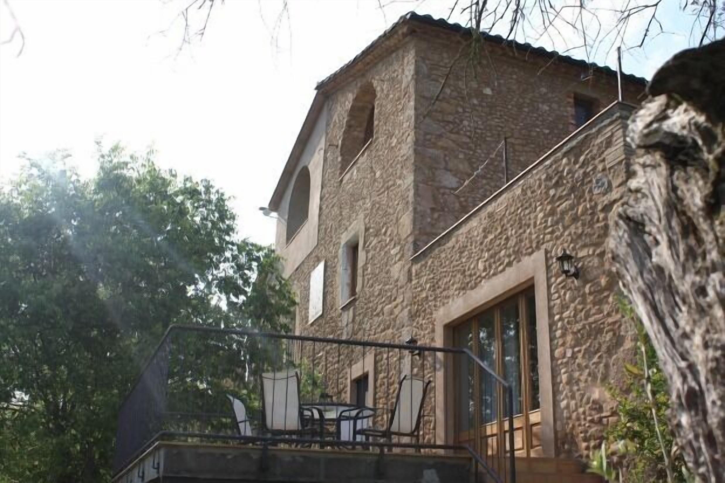 A stone building with a balcony and outdoor seating.