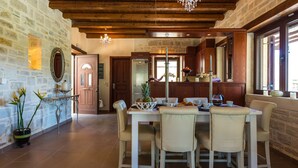 A dining area with a stone wall, wooden ceiling, and a chandelier.