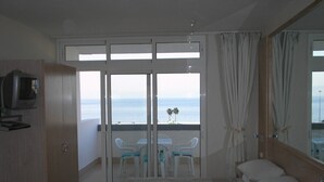 A bedroom with a bed, a TV, a balcony with a table and chairs, and a view of the sea. - Remarkable Value, Unbeatable Location, Spectacular Views (Arona)