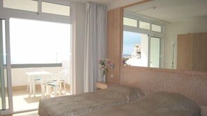A hotel room with a bed, a desk, and a chair. There is a balcony with a table and chairs outside. - Remarkable Value, Unbeatable Location, Spectacular Views (Arona)