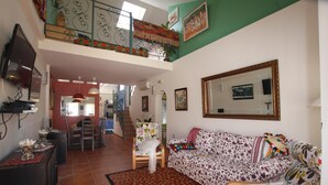 Una sala de estar con un sofá, una mesa de comedor y una escalera que sube a un nivel superior.