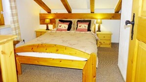 Een slaapkamer met een houten bed, twee nachtkastjes, een lamp, een deur en een raam met gordijn.