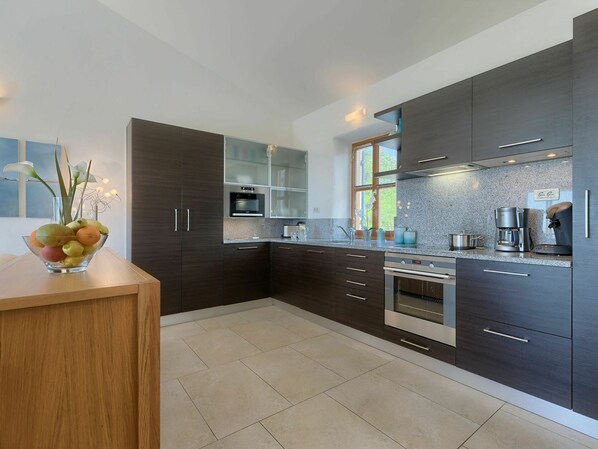 A modern kitchen with dark cabinetry, stainless steel appliances, and a granite countertop.