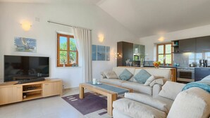 A modern living room with a flat-screen TV, a sofa, a coffee table, and a kitchen area with a stove and microwave. - Nice apartment in villa for 6 guests with WIFI, pool, A/C, TV and terrace (Umag)