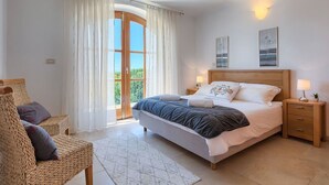 A bedroom with a bed, a nightstand, a chair, a window with curtains, and a view of greenery outside. - Nice apartment in villa for 6 guests with WIFI, pool, A/C, TV and terrace (Umag)