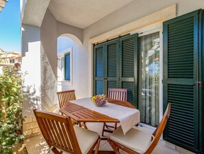 A patio with a table and chairs, a bowl of fruit, and green shutters.