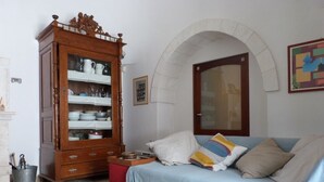 Ein Zimmer mit einem Holzkasten, einer Couch mit Kissen, einem Fliesenboden und einer Tür mit Bogen.