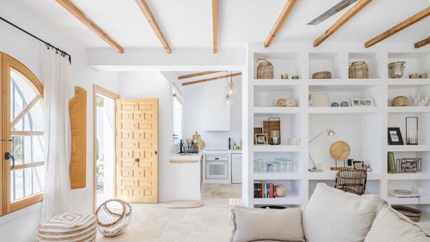 A spacious living room with a sofa, a coffee table with fruit, and a bookshelf filled with books and decorative items. - SODA Y LIMÓN - Amazing sea and mountain views, private (heated) pool, air conditioning (Sayalonga)