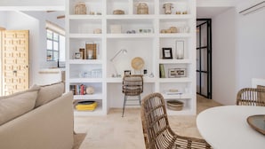 A modern living room with a white bookshelf, wicker chairs, and a round table. - SODA Y LIMÓN - Amazing sea and mountain views, private (heated) pool, air conditioning (Sayalonga)