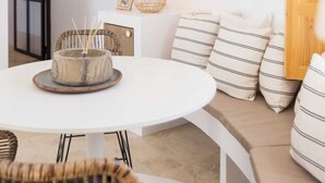 A cozy living room with a round white table, a wicker lamp, and striped cushions on a sofa. - SODA Y LIMÓN - Amazing sea and mountain views, private (heated) pool, air conditioning (Sayalonga)