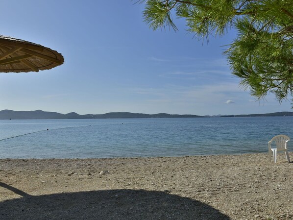Ein Strand mit freiem Blick auf das Meer und entfernte Berge.