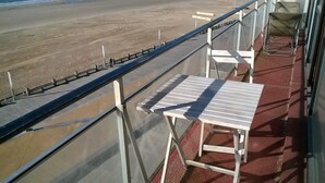 Varanda com guarda-corpo de metal com vista para a praia.