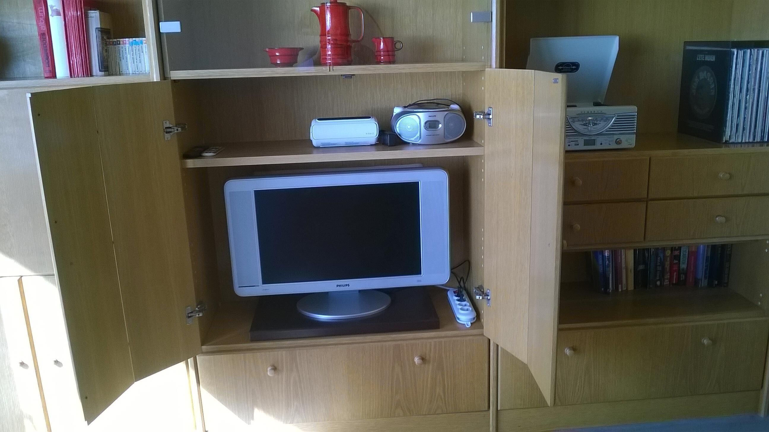 Et træskab med en Philips-skærm, en radio og en bærbar computer ovenpå.