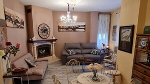 Ein Wohnzimmer mit einer Couch, einem Esstisch mit Stühlen, einer Kristallleuchtre und einem Kamin.