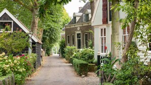 A narrow cobblestone path flanked by traditional European-style buildings with brick facades and white trim. - Luxury B&B in a historic village 10 km from downtown Amsterdam. Peace & comfort. (Broek in Waterland)