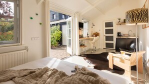 A bedroom with a bed, a desk, a chair, a TV, and a window. - Luxury B&B in a historic village 10 km from downtown Amsterdam. Peace & comfort. (Broek in Waterland)
