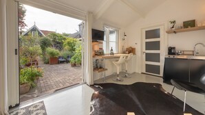 A modern kitchen with a black countertop, white chairs, and a cowhide rug. - Luxury B&B in a historic village 10 km from downtown Amsterdam. Peace & comfort. (Broek in Waterland)
