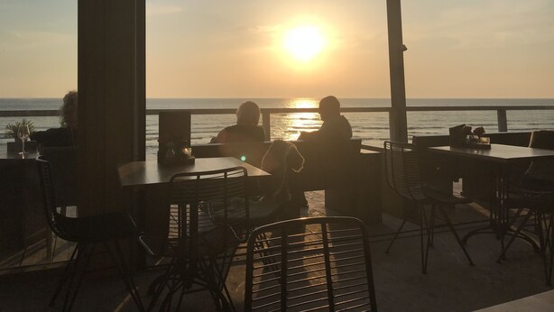 An outdoor seating area with tables and chairs facing the ocean at sunset. - Luxury B&B in a historic village 10 km from downtown Amsterdam. Peace & comfort. (Broek in Waterland)