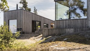 A modern wooden building with large windows and a flat roof. - Exclusive architectural house in archipelago (Stockholm)