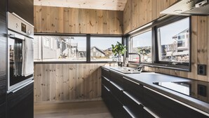 Een moderne keuken met houten lambrisering, een groot raam en een roestvrijstalen koelkast.