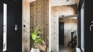 Een modern interieur met houten paneelwanden, een potplant en een trap naar een andere kamer.