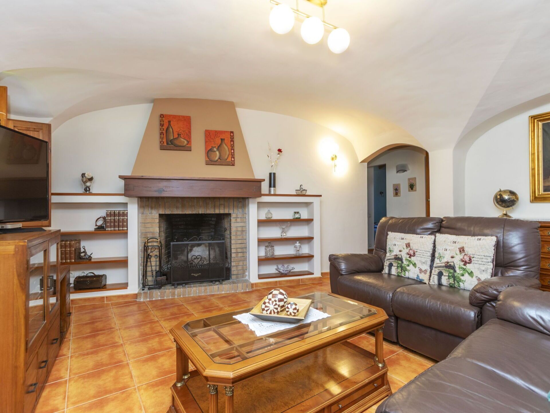 Una sala de estar con chimenea, sofá de cuero y televisor.