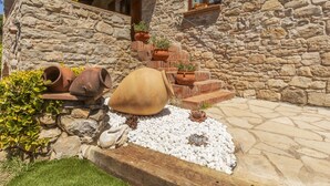 A stone building with a rustic exterior, a wooden staircase leading to a window, and several terracotta pots on the ground. - Beautiful private villa for 8 guests with WIFI, private pool, TV, patio and pets allowed (Calonge)