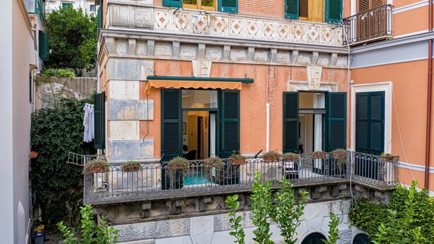 A traditional Italian building with a stone facade, green shutters, and a small balcony with potted plants. - Dora Flat   Amalfi centre (doorbell)